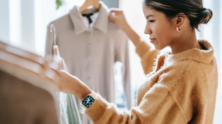 Concentrated woman with hangers and clothes