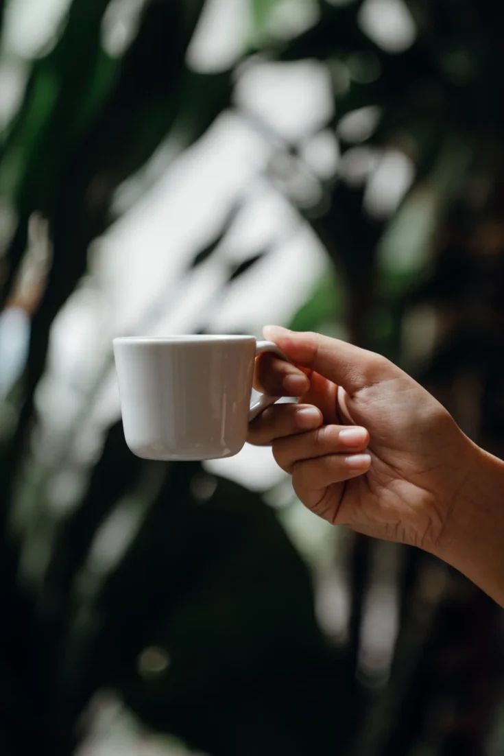 Crop person with cup of coffee in hand