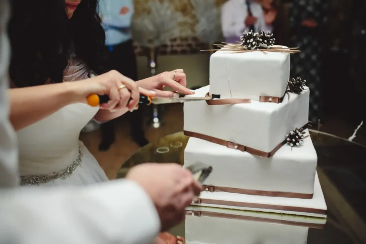 bride and groom slicing the white multi-tier cake