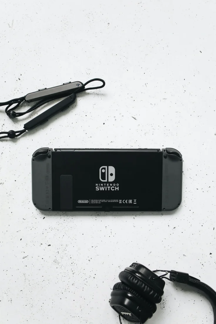 nintendo switch and a black headphones on a white surface